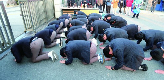 每年韩国的高考考场外常有学弟给学长下跪磕头祈福